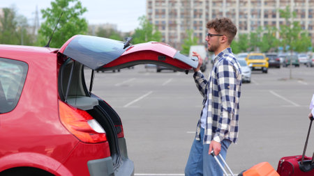 Young people leaving on road trip adventure, putting suitcase and travel bags in the trunk in the car. Trip, transportation, relationships, lifestyle concept. Slow motionの写真素材