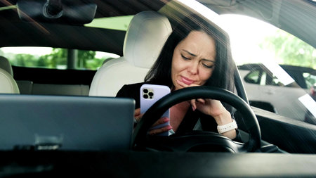SCalm lady holding smartphone while reading message, sitting in the car. Transport, technology,...