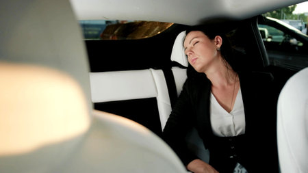Young woman resting while sleeping, sitting on the back seat in the taxi. Transport, trip, business concept.の写真素材