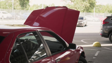 Happy young male driver closing car hood on the parking in the city.の写真素材