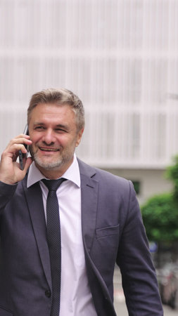Happy adult man in suit talking on the mobile phone in the city.