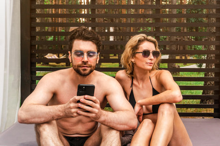 Young couple in sunglasses resting in a cozy pergola in a recreation park. Leisure activity and summer vacation conceptの写真素材