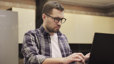 Successful freelancer working online on computer, sitting in modern kitchen