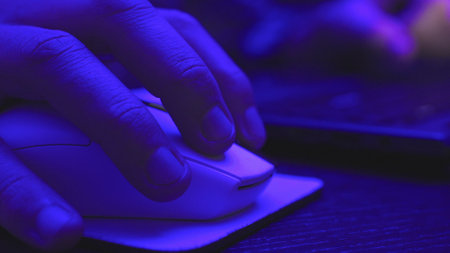 Man using computer mouse when working online desk at nightの写真素材