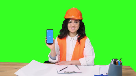 Happy female architect with phone, showing ok gesture on the chroma keyの写真素材