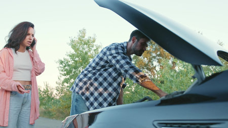 Man opening car hood of a broken car, woman talking on the phone. Slow motion