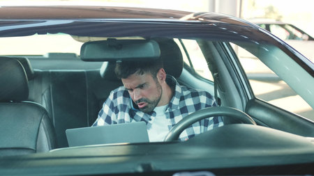 Guy using smartphone while working with laptop in the car. Slow motion