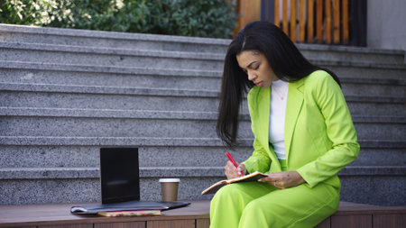 Pretty young woman studying outside with notebookの写真素材