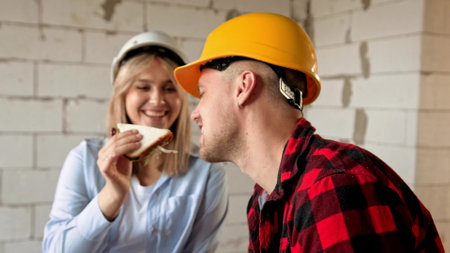 Construction worker treating her coworker with nourishing lunch on siteの写真素材