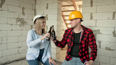 Cheerful builders relaxing with beer during work break on siteの写真素材