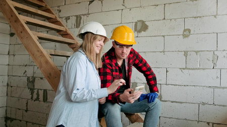 Housebuilders watching something on phone screen in building under constructionの写真素材