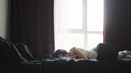 Tired woman resting after work on the laptop, sleeping in the bedroomの写真素材