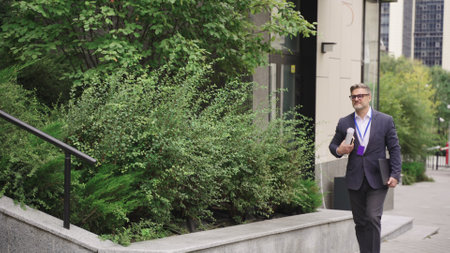Businessman holding laptop and documents, walking in the city. Slow motionの写真素材