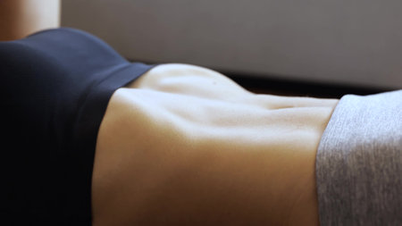 Young woman has workout at home during quarantine. Close up and side view of model training her abs muscles. Exercising hard.の写真素材