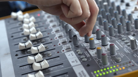 Young man in sound recording studio. Close up video of male hands turning and adjusting electronics and equalizer.の写真素材