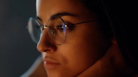 Young woman at home during quarantine. Close up and cut view of serious calm concentrated girl in glasses watching video. Reflection.の写真素材