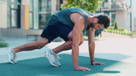 Young man exercising outside. Video process of guy doing mountain climber exercise. Running fast in horizontal position on the same place. Training near urban view.の写真素材