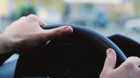 Young man inside car. Close up of hands on steering wheel. Driving car fast and accurate. Blurred background.の写真素材