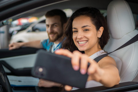 Happy young couple enjoying the trip hwile woman holding smartphone and making selfie together....