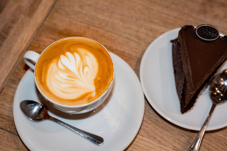 Cup of cappuccino and chocolate cake on wooden tableの写真素材