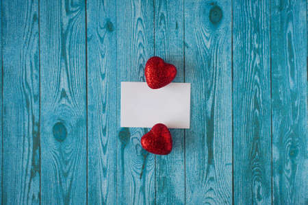 two red hearts with an empty plate on a blue background with wood textureの写真素材