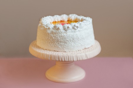 frosted white cake on stand on the pink tableの写真素材