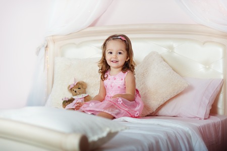 house. bedroom. room a little girl. Very beautiful girl playing with toys on the bed.の写真素材