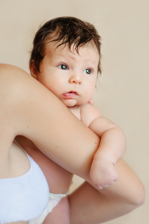 Adorable baby holding tight mothers neck and shoulder.の写真素材