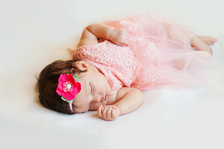 Close-up beautiful sleeping baby girl. Newborn  , asleep on a blanket.  portrait of  , two month old,    wearing  large, fabric rose headband. Closeup photoの写真素材