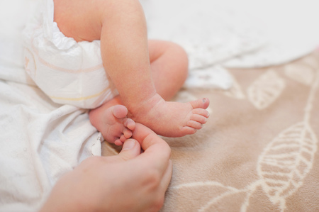 Baby feet cupped into mothers lovely hands with soft focus on babies footの写真素材