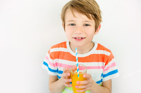 Portrait of happy little boy drinking orange juice.の写真素材