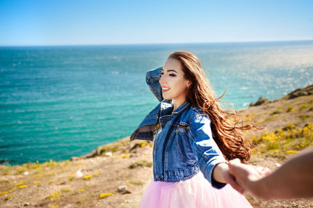 Follow me there. Beautiful young woman holds the mans hand and indicate a idyllic place to relax. Best friends couple walking hand in hand and discover new place. Carefree modern travel concept.の写真素材