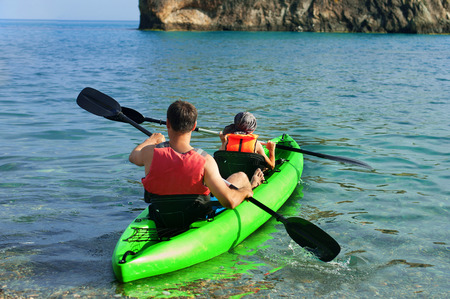 Two people - an adult and a child father and son in life jackets sail on inflatable boats during hike at summerの写真素材