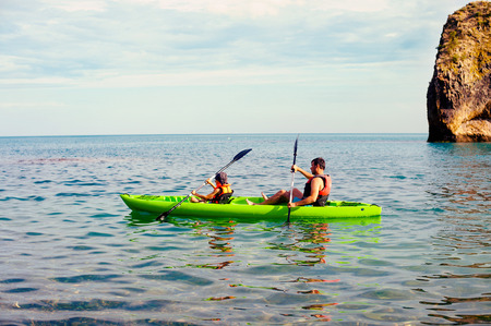 Two people - an adult and a child father and son in life jackets sail on inflatable boats during hike at summerの写真素材