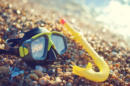 diving concept - black mask and snorkel on Pebble beachの写真素材