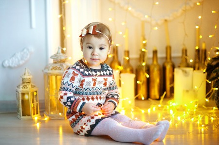 Portrait of pretty little girl near a fireplace in Christmas on the background of the fir-treeの写真素材