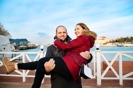 Happy young couple in love hugging enjoys spring day, loving man holding on hands his woman carefree together outdoors walking at parkの写真素材
