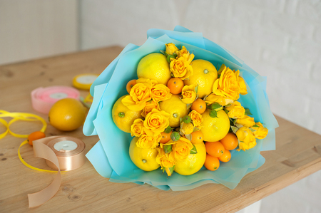 freshly made bouquet of fruit and flowers. Yellow bouquet in blue wrapperの写真素材