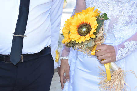 groom with black tie and bride in white with a bouquet of yellow sunflowers. High quality photoの写真素材