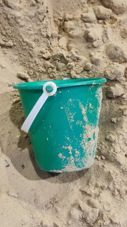 green plastic bucket lies in the sand, children's toy, object, beach. High quality photoの写真素材
