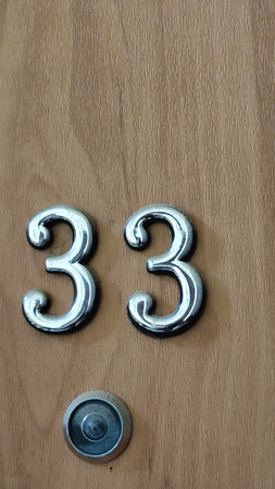 numbers 33 on a wooden exterior apartment door, symbol objects. High quality photo