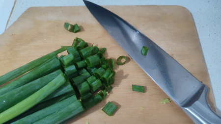 health food green fresh chopped onion, aluminum knife, background healthy cooking, wooden kitchen board. High quality photoの写真素材