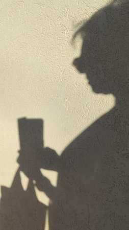 shadow of a man on the wall, woman with a mobile phone and a backpack, tourist image travel symbol....