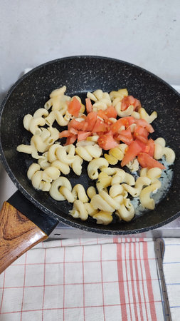 boiled pasta with tomatoes in a frying pan, healthy food, breakfast cooking lunch. High quality photoの写真素材