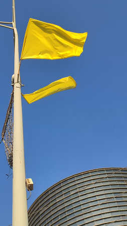 yellow flags on a pole, blue sky, landscape modern buildings business architecture symbol of solidarity with the hostages. High quality photoの写真素材