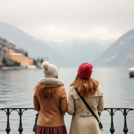 two girls friends in coats and hats travel lake, stand with their backs in Europe in winter. High quality photoの写真素材