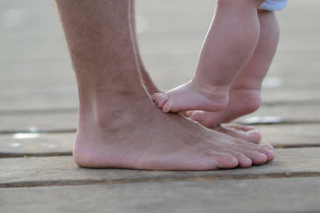 Newborn child standing on fathers feetの写真素材