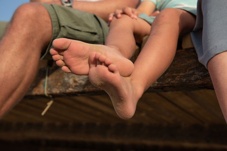Feet of a family covered in sand on the beach.