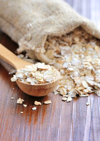 Oat flakes in wooden spoon on wooden backgroundの写真素材