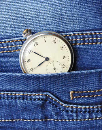 Old pocket watch in the pocket of blue jeansの写真素材